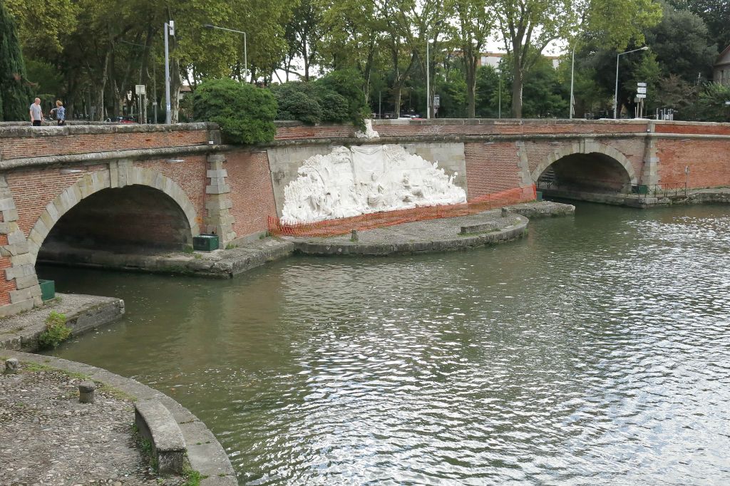 Entrée vers le Canal du Midi (à gauche), et vers le Canal de Brienne (à droite). Au centre le bas-relief des Ponts-Jumeaux réalisé en 1775